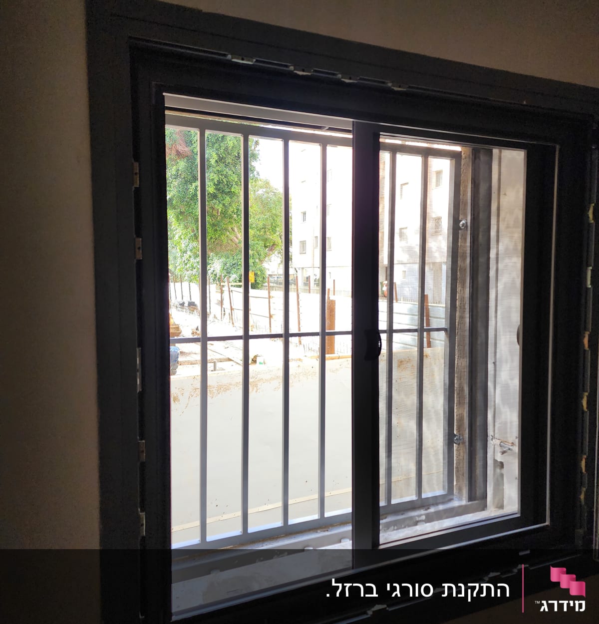 חלון עם מסגרת מתכת וסורגים חיצוניים